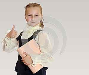 Girl schoolgirl with a book in hand shows thumb.