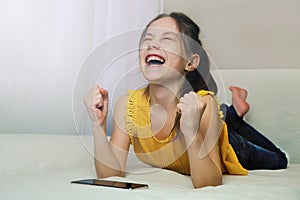 Girl schoolgirl experiences the joy of victory playing on a cell phone