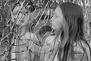 Girl schoolgirl looks sad in the broken mirror. Black and white photo