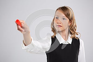 Girl schoolgirl writes on the Board with red chalk