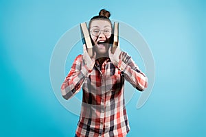 The girl screams joyfully, clutching large books to her head with her hands