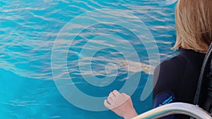 a girl with scuba diving is sitting on board a yacht, preparing to dive, diving in the sea