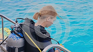 a girl with scuba diving is sitting on board a yacht, preparing to dive, diving in the sea