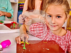 Girl sculpt of plasticine on desk in photo