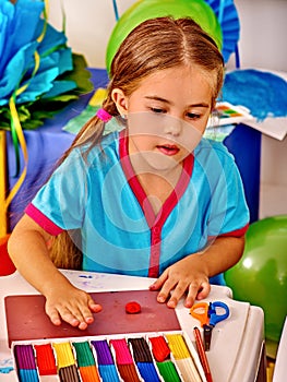 Girl sculpt of plasticine on desk in photo