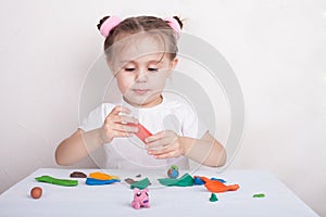 Girl sculpts from plasticine pink pig