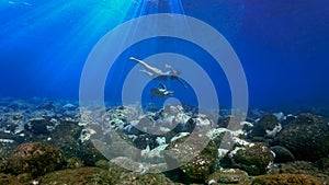 Girl and sea turtle swimming underwater