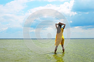Girl in sea water. Sea landscape. Sea bank and cloudy sky. Green water surface, forest on horizont line and blue sky with clouds.