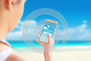 The girl searches for new destinations for travel and vacation with smart phone app on beach