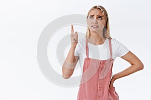 Girl see strange, unreasonable price for goods, looking skeptical and sipleased. Attractive blond woman in casual outfit