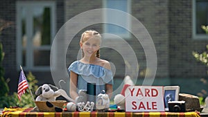 Girl selling old toys on yard sale, earning pocket money, young business lady