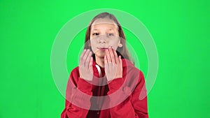 Girl is sending blow kisses and smiling on green background. Slow motion