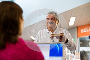 Girl and senior man returning book in library