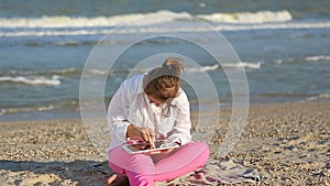 Girl seventeen-year-old with Down syndrome on the beach play with the tablet.