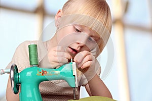 Girl sew on a children's sewing machine.