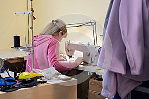 Girl sews on a professional sewing machine in the workshop