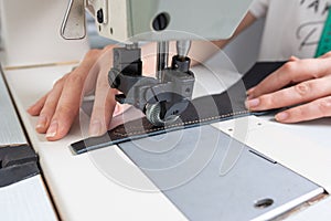 Girl sews on a sewing machine scribbles fabric and leather making a product