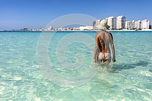 Girl in sexy bikini entering the blue seagull beach of Cancun city in Riviera Maya of Mexico. Turquoise caribbean beach.