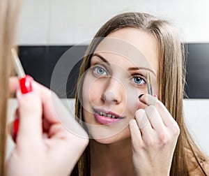 Girl shaping eyebrows with tweezer