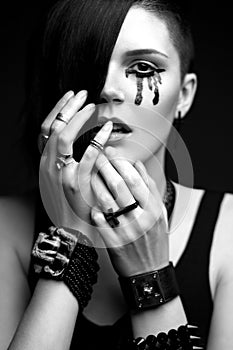 Girl with shaved head in art gothic style with black paint on his face and gothic accessories.
