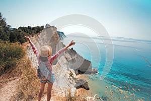 Girl  and sheer white cliffs of Cape Drastis near Peroulades