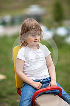 Girl in a shirt on a swing outside, spring