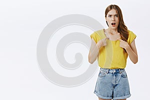 Girl shocked being insulted by stranger standing displeased and offended pointing at herself with opened mouth staring