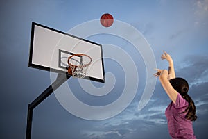 Girl shooting a basketball at an outdoor court