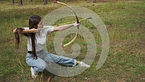 Girl shooting with bow from a sitting position