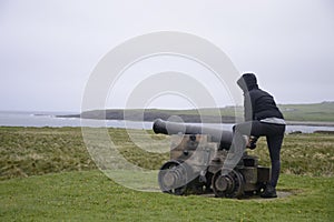Girl shooting cannon Orkney coastline cliff landscape