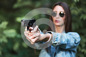 Girl shooting instructor with a gun in his hand aiming at the target