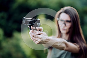 Girl shooting instructor with a gun in his hand aiming at the target