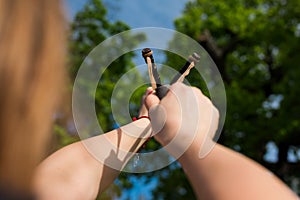 Girl shooting from the professional wooden slingshot