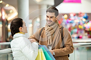 Girl with shopping bags talking to smiling man