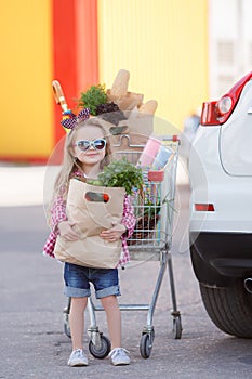 Girl with a shopping cart full of groceries near the car