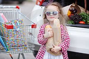 Girl with a shopping cart full of groceries near the car