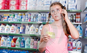 Girl with shopping list speaking on smartphone