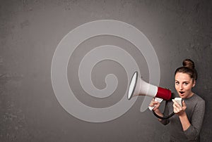 Girl shouting into megaphone on copy space background