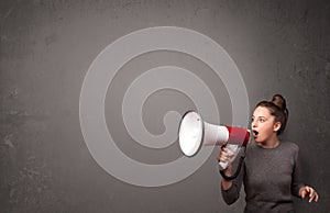 Girl shouting into megaphone on copy space background