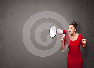 Girl shouting into megaphone on copy space background