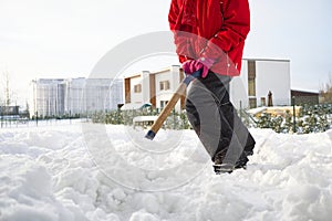 Girl shoveling snow on home drive way. Beautiful snowy garden or front yard. Teenager removing snow with a shovel in the