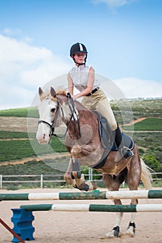 Girl show jumping with a Sabino paint horse