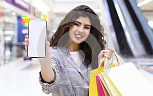 Girl showing cellphone after shopping in big mall