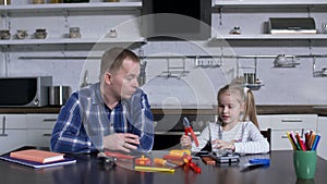 Girl showing dad pliers during home craft lesson