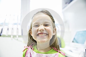 Girl showing her healthy milk teeth at dental office