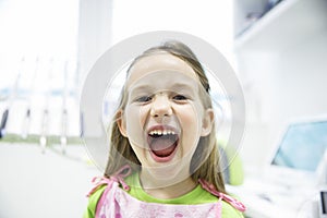 Girl showing her healthy milk teeth at dental office