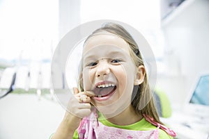 Girl showing her healthy milk teeth at dental office