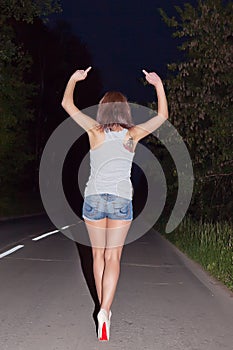 Girl showing obscene gestures at walking distance along road