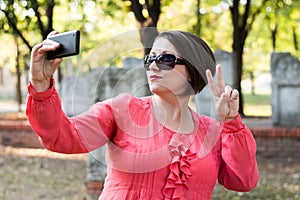 Girl Showing Peace Sign and Taking Selfie in a Park