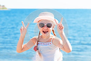 Girl showing sign victory with fingers near sea